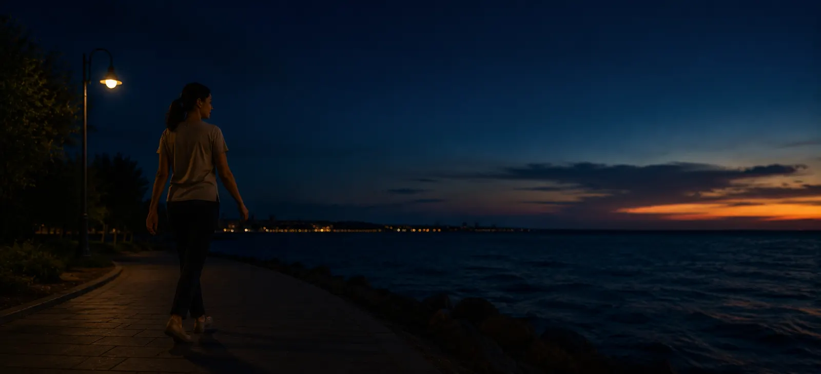 A person walking along a waterfront path at dusk